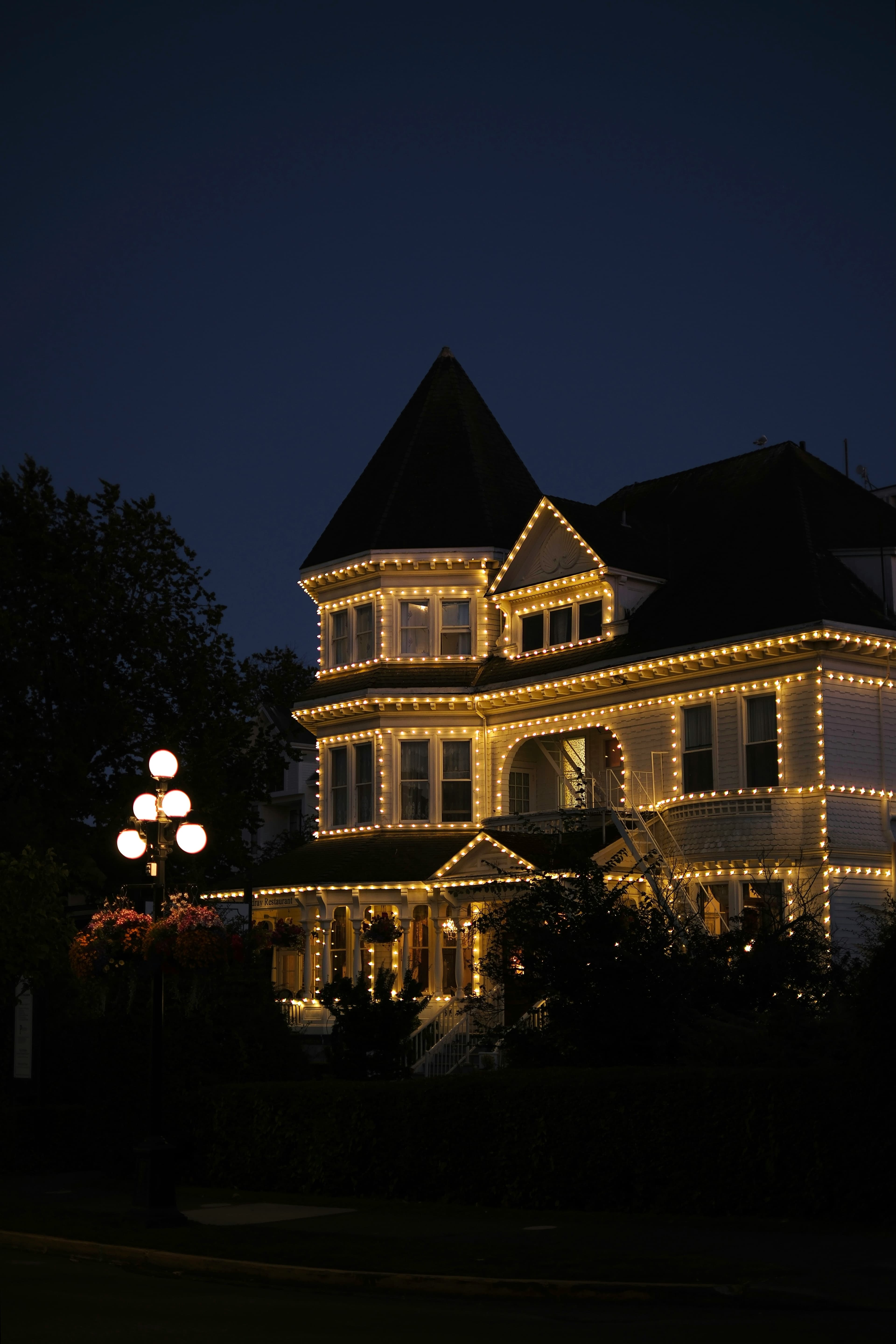 Warm white lights outlining a building’s rooflines and windows at dusk