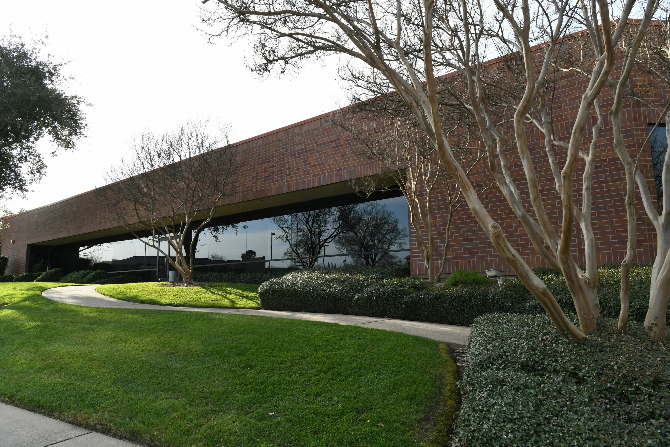 Shaped shrubs beside a curved walkway and brick building